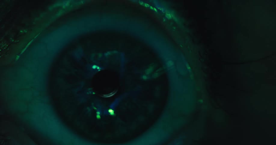 A dramatic macro shot shows a human eye transforming under changing light, eventually glowing with a strange green bioluminescence in the dark