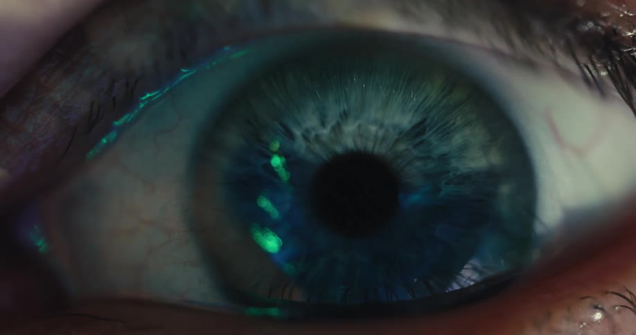 An extreme macro shot of a human eye dilating as light fills the iris, revealing intricate details