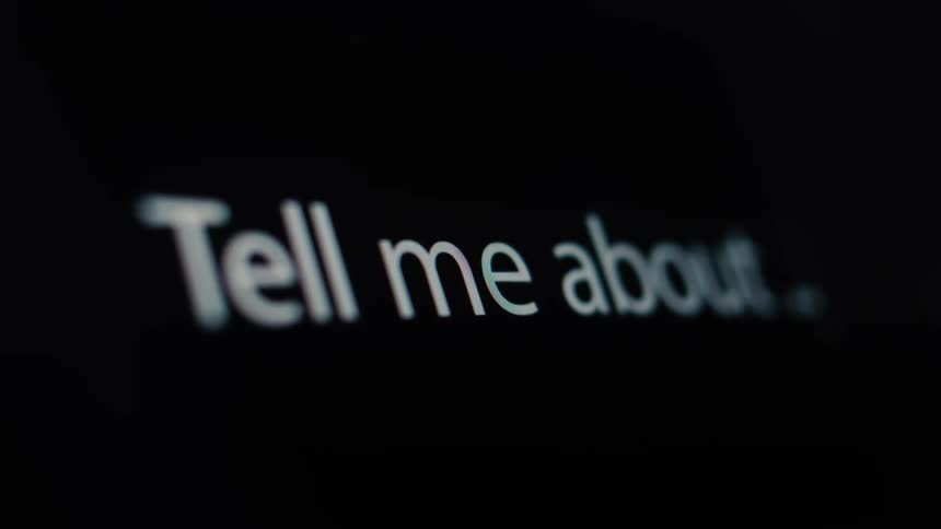 A macro shot shows the text 'Tell me about...' being typed onto a dark computer screen
