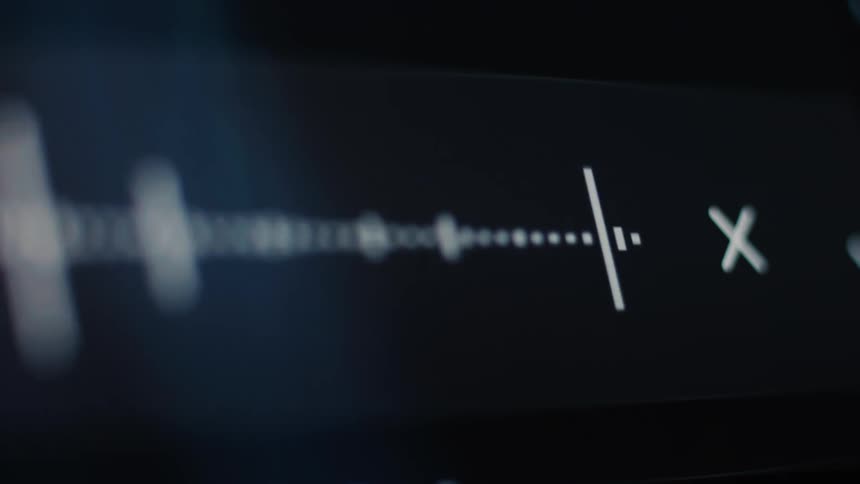 An abstract, close-up shot shows a digital audio waveform moving across a dark screen display