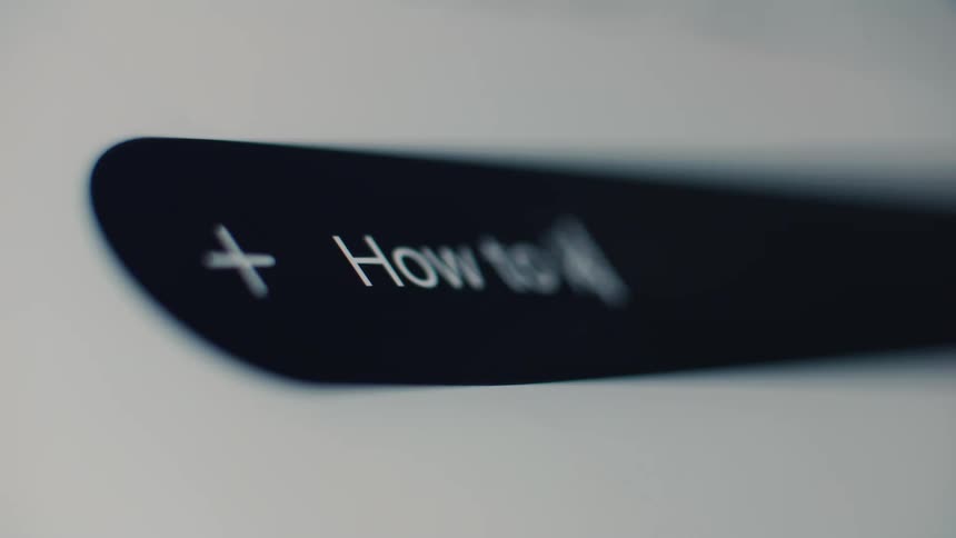 A macro shot shows someone typing 'How to keep in' into a dark mode internet search bar on a digital screen