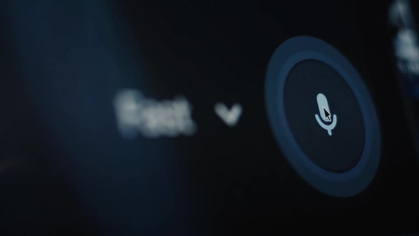 A macro shot shows a cursor activating a microphone icon for voice search on a computer screen, with a blue ring pulsing around it