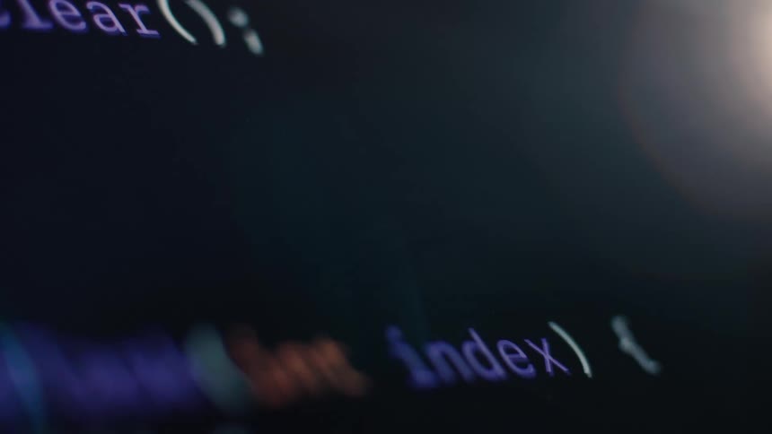 A close-up, stylized shot of computer code scrolling down a dark screen with a prominent lens flare