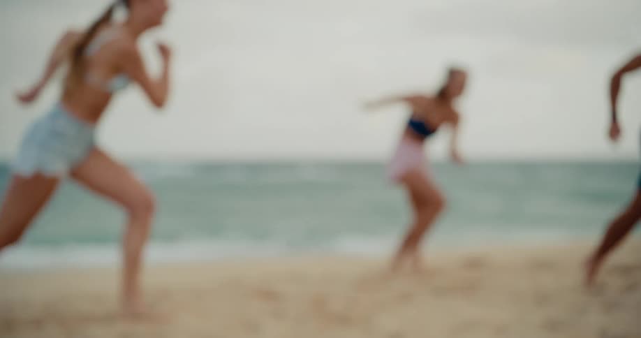 Slow motion shot of a man and women playing soccer on the beach by the ocean