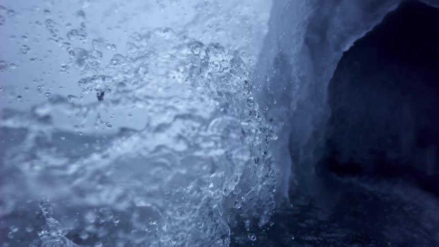 A stream of water splashes against an ice formation in mesmerizing super slow motion