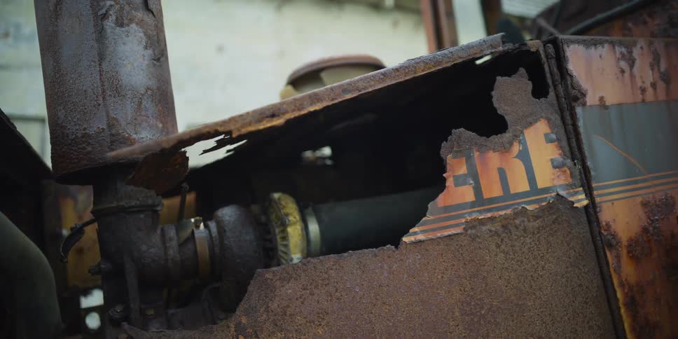 A slow pan reveals the rusted and decaying engine of an abandoned old John Deere tractor