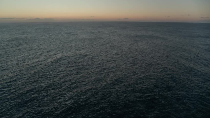 A serene and expansive view of the open ocean stretching to the horizon at twilight