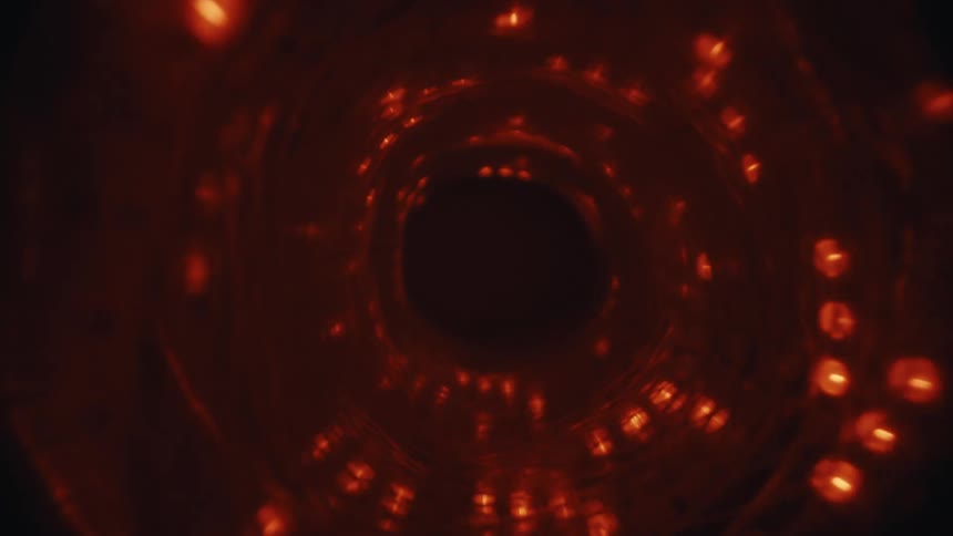 Traveling through a mesmerizing, abstract tunnel of swirling red lights in the darkness