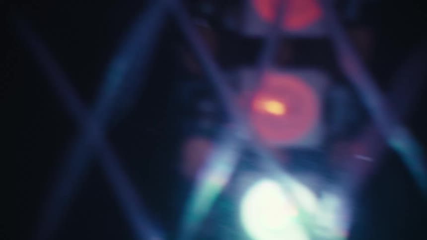 An abstract close-up shot of a blurry, flashing LED light panel with red and blue lights creating a bokeh effect against a dark background