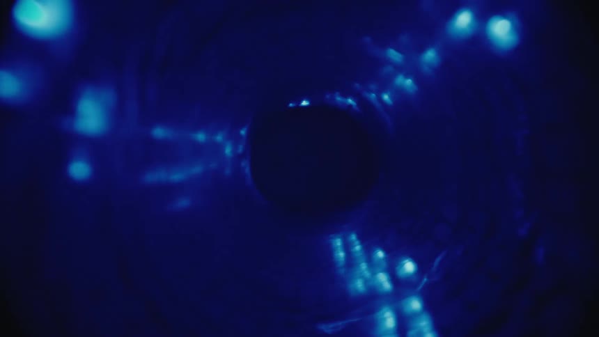 Camera travels through a dark blue abstract tunnel with swirling glowing lights