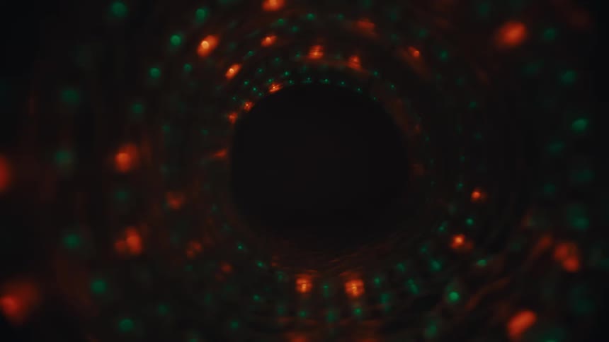 Moving through a dark, abstract tunnel of swirling red and green lights that fades to black