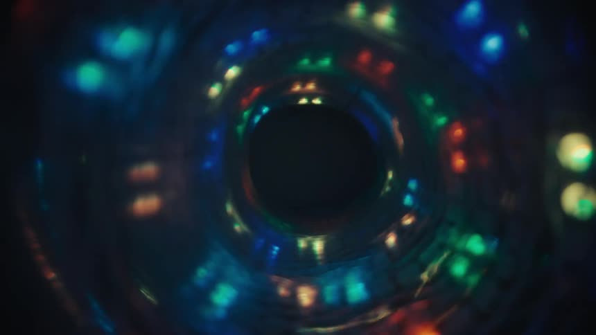 A mesmerizing abstract vortex of swirling, multicolored bokeh lights moves through a dark space