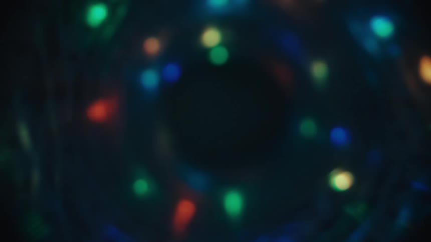 A mesmerizing backward journey through a swirling tunnel of colorful bokeh lights against a dark background