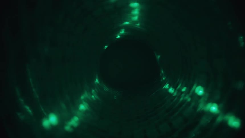 A mesmerizing point-of-view journey through a dark, swirling tunnel illuminated by abstract green lights