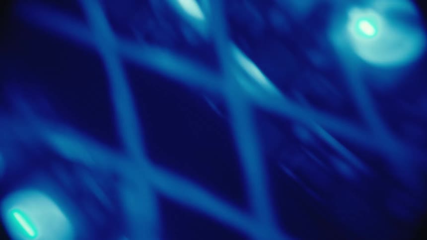 An abstract and soft-focused close-up of a grid of shifting and changing LED lights in the dark