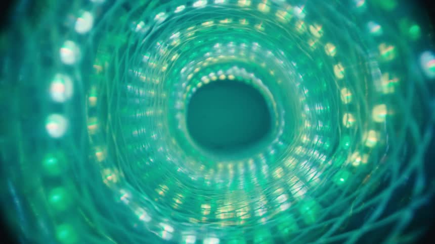 A slow-motion macro shot moves forward through a mesmerizing spiral tunnel of glowing green lights