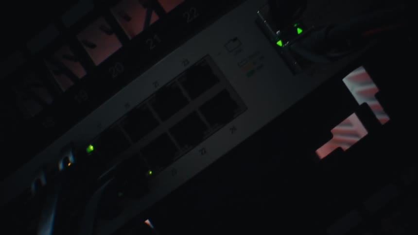 Dutch angle close-up of a network router with blinking green LED lights in a dark server room