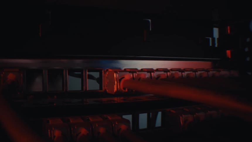 Macro dolly shot reveals a blinking ethernet port on a network switch in a dark server room with red lighting
