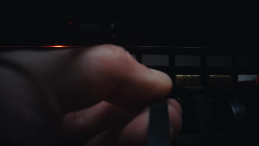 An IT technician's hand slowly plugs a network cable into a server rack inside a dark data center