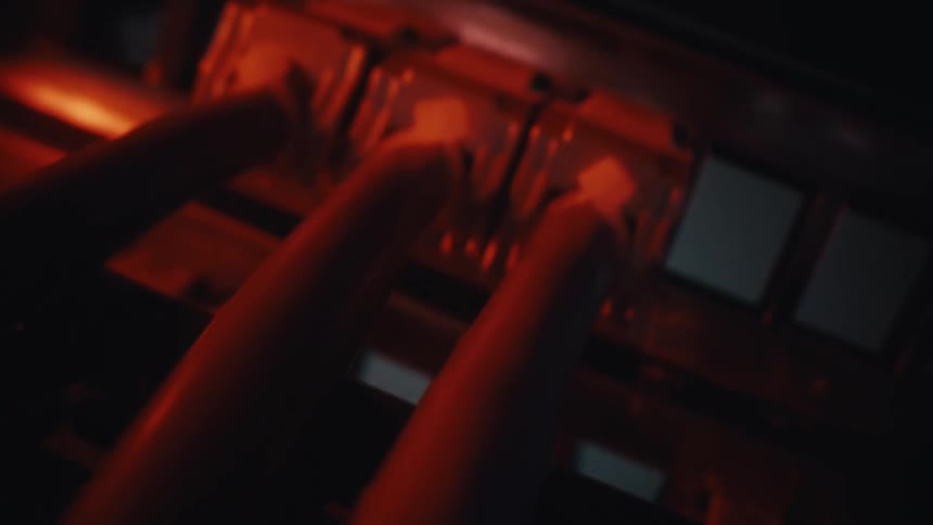 A dramatic close-up shot of red ethernet cables plugged into a network switch in a dark, modern server room