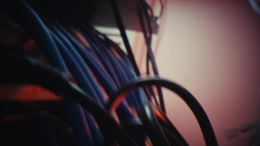 An atmospheric macro shot slowly explores a dense network of dark electrical wires and computer cables