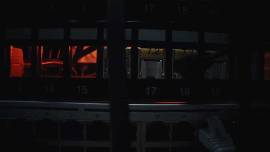 A slow cinematic zoom into a network switch with blinking lights in a dark server room