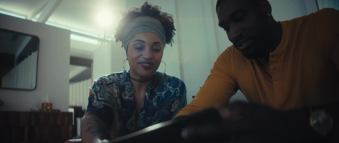 Low-angle shot of a smiling man and woman browsing on a digital tablet in a cozy, modern home