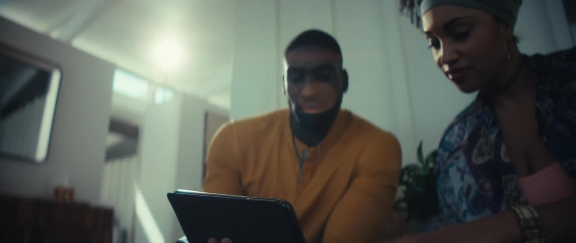 A young African American couple collaborates on a project using a digital tablet in their modern, sunlit home