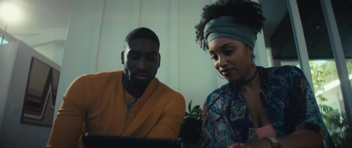 A stylish couple discusses plans on a digital tablet while sitting together in their bright, modern home
