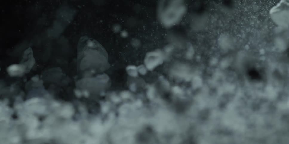A slow-motion macro shot of fine white powder raining down and settling against a black background before inverting colors