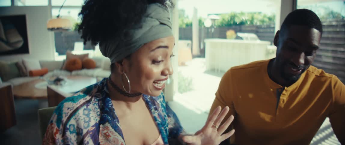 An expressive couple smiles and talks animatedly while enjoying an activity together in their bright, modern home