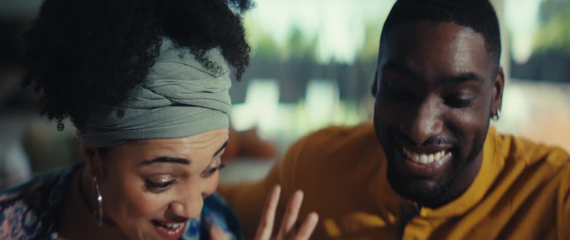 A joyful African American couple smiles and laughs together in a heartwarming slow-motion close-up