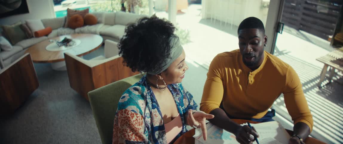 High-angle shot zooms in on a happy couple working together on their home finances, reviewing charts and using a calculator at their dining table