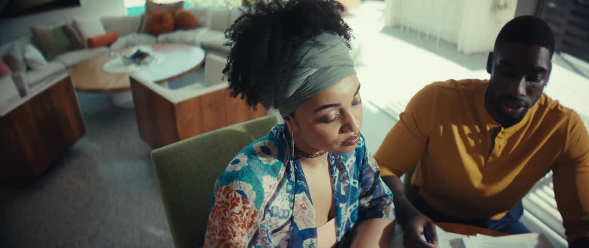 High-angle shot of a couple reviewing financial charts at their dining table, slowly zooming in on the woman's thoughtful expression