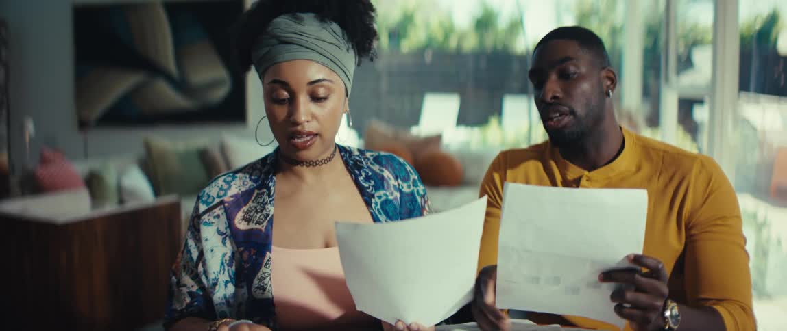 A concerned young couple review their finances and bills together, discussing paperwork in their modern living room