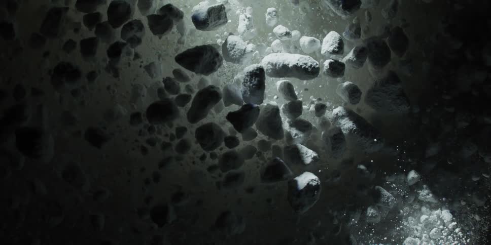 Slow motion macro shot of white porous granules floating and dispersing in the dark