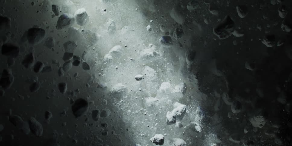 A dramatic close-up of a white powdered substance exploding and floating in the darkness