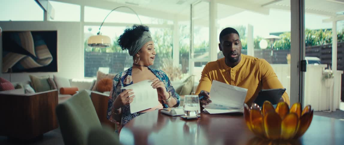 A stylish young couple sitting at their dining table gets excited after working through their finances together