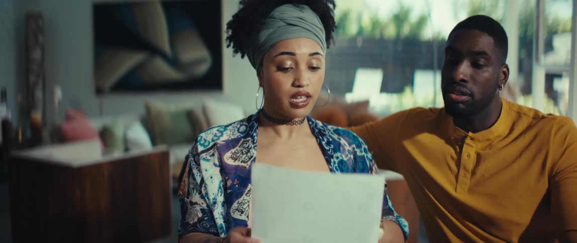 A concerned young couple sits together in their living room, seriously reviewing and discussing important documents