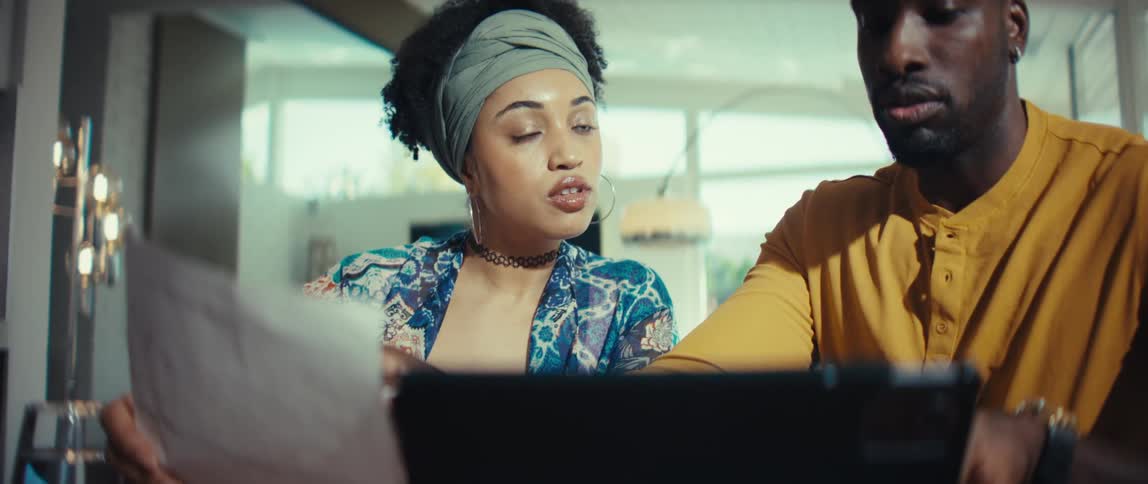 A young Black man and woman have a serious discussion as they work together on a project in a modern office space