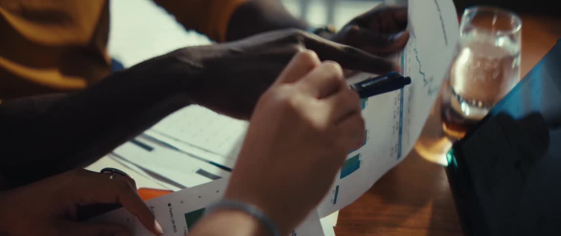 Close-up of colleagues collaborating over financial performance charts and graphs in a business meeting