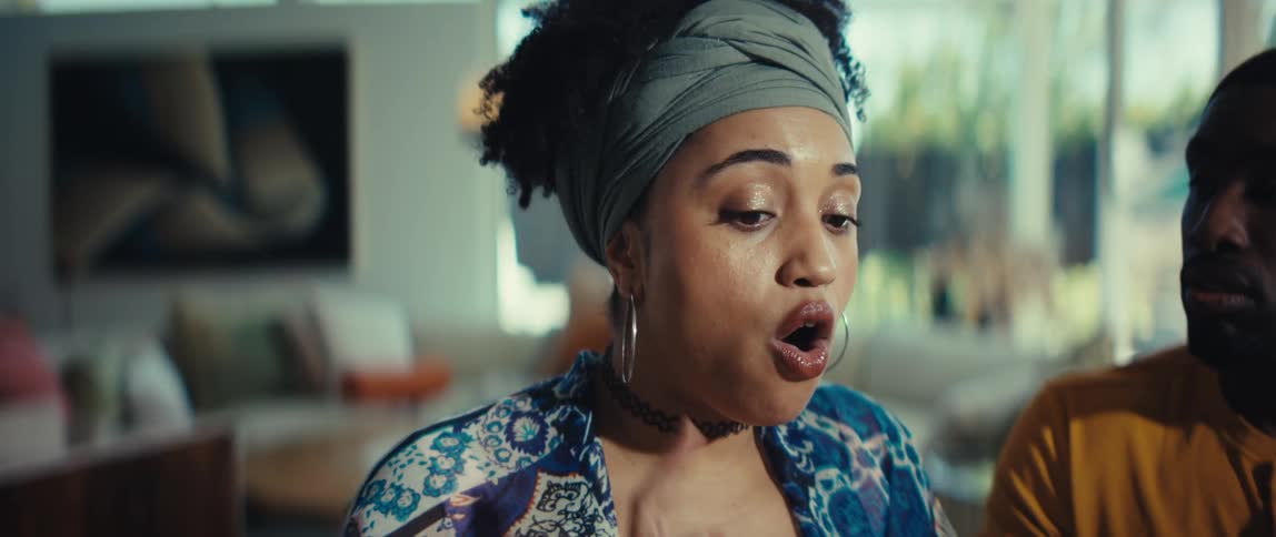 A stylish young Black woman with a headwrap has an animated conversation, her face showing a range of expressive emotions in slow motion
