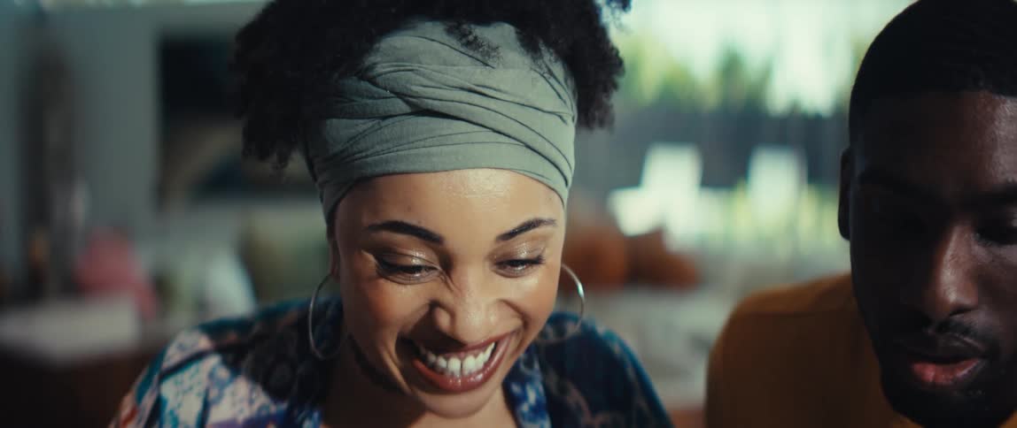 Close-up of a beautiful young woman's face as she breaks into a wide, happy smile and laugh