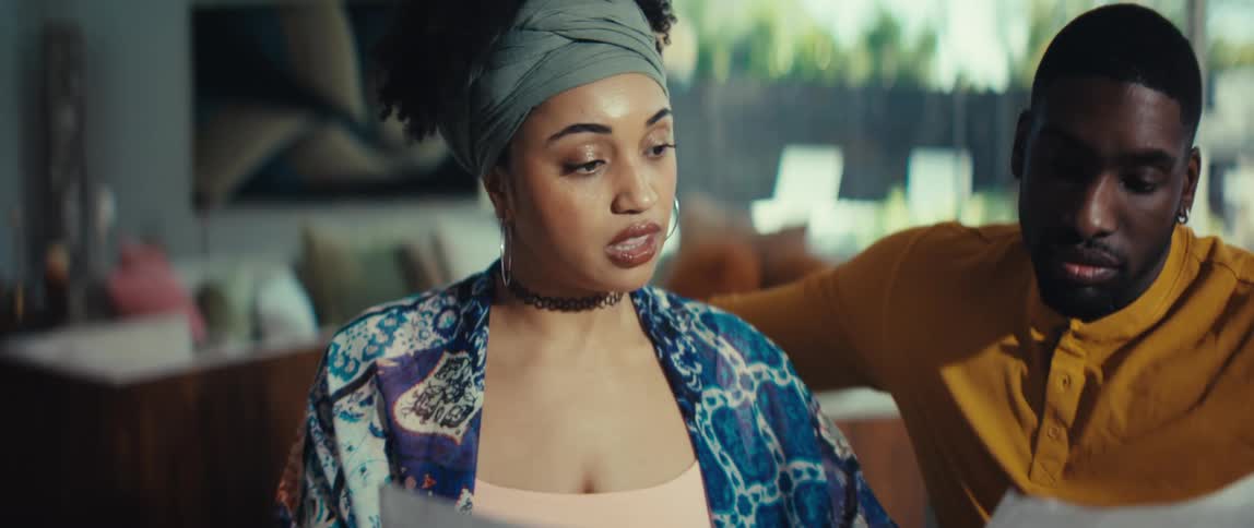 A stylish Black couple expresses concern and surprise while reviewing their financial bills together at home