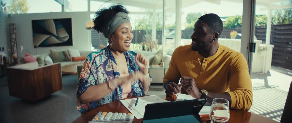 An overjoyed young couple shares a celebratory hug and kiss after achieving a financial goal together at their dining table
