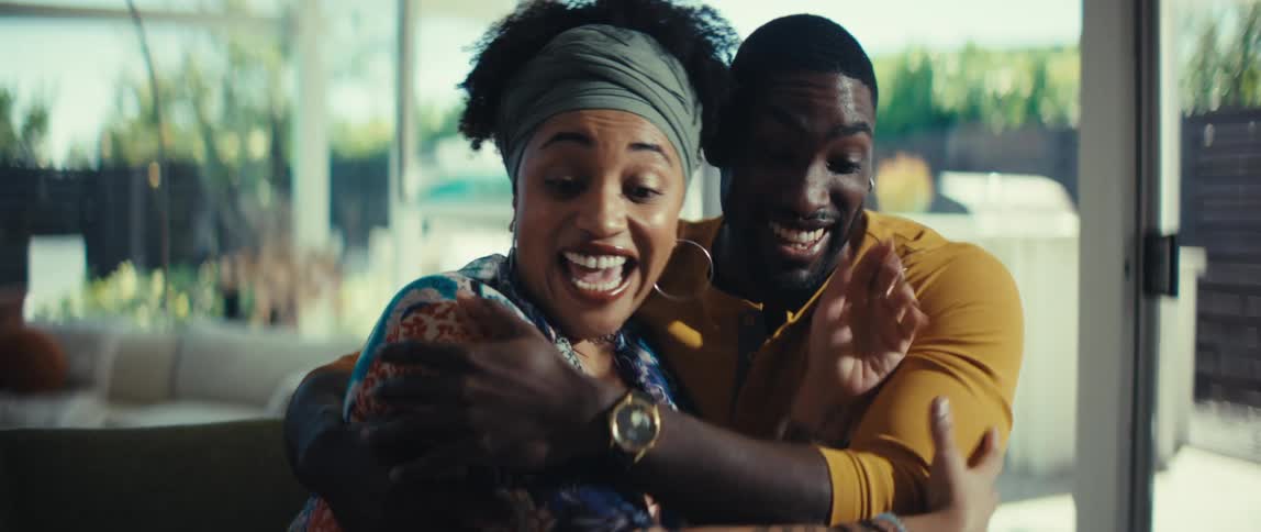 An overjoyed young couple receives good news about their finances, celebrating with a happy hug in their sunlit home