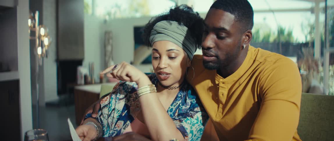 A happy young couple smiles and cuddles while reviewing their household finances together at the table