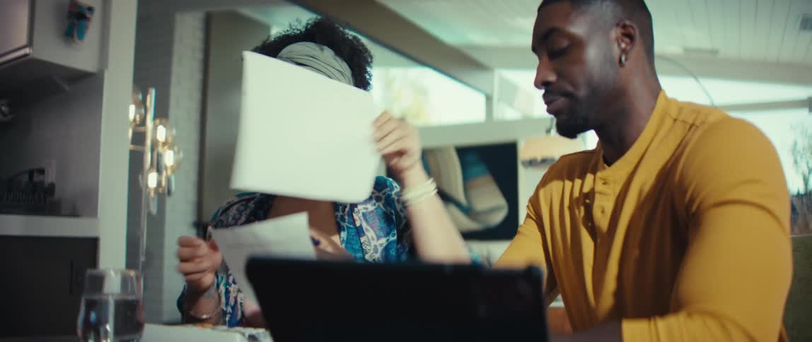 A concerned young couple goes over their finances and bills together using a laptop in their modern home
