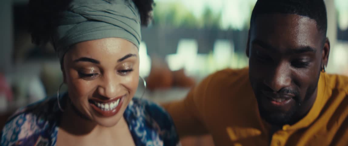 A close-up shot of a happy young Black couple smiling and looking down together with joy and excitement