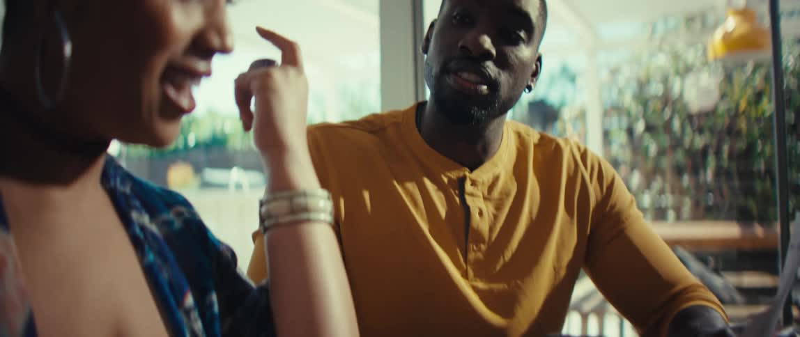 Slow-motion shot of a happy African American couple sitting at a table at home, calculating their finances and laughing together
